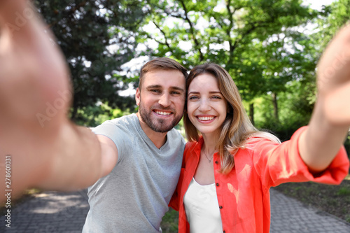 Happy young couple taking selfie in park