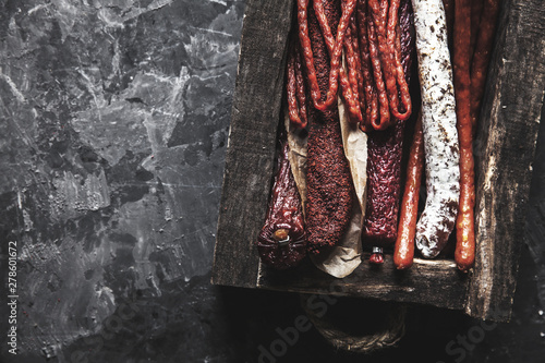 Salami with spices in an old tray. On a dark gray background