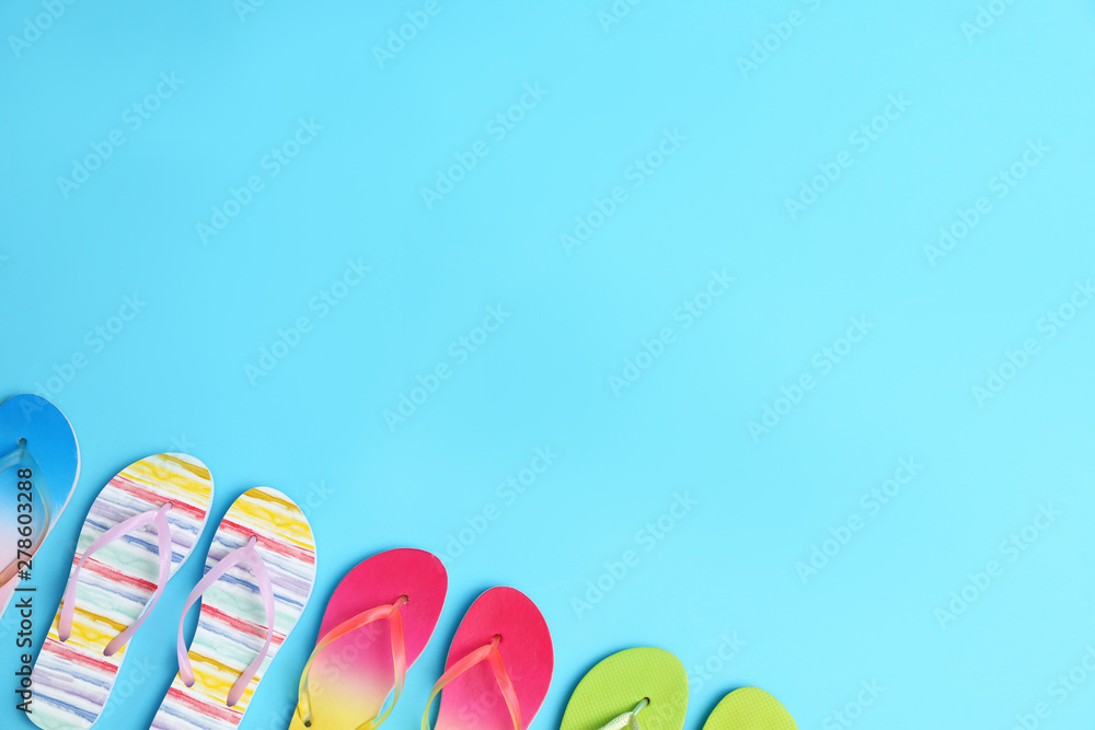 Different flip flops and space for text on blue background, flat lay. Summer beach accessories