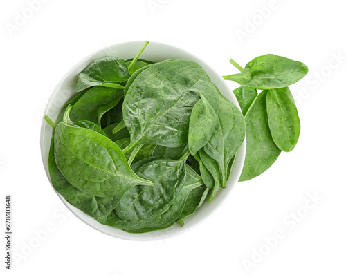 Fresh green healthy baby spinach leaves in ceramic bowl isolated on white, top view