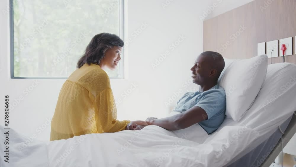 Wife Visiting And Talking With Patient Husband In Hospital Bed Wife Visiting And Talking With Patient Husband In Hospital Bed