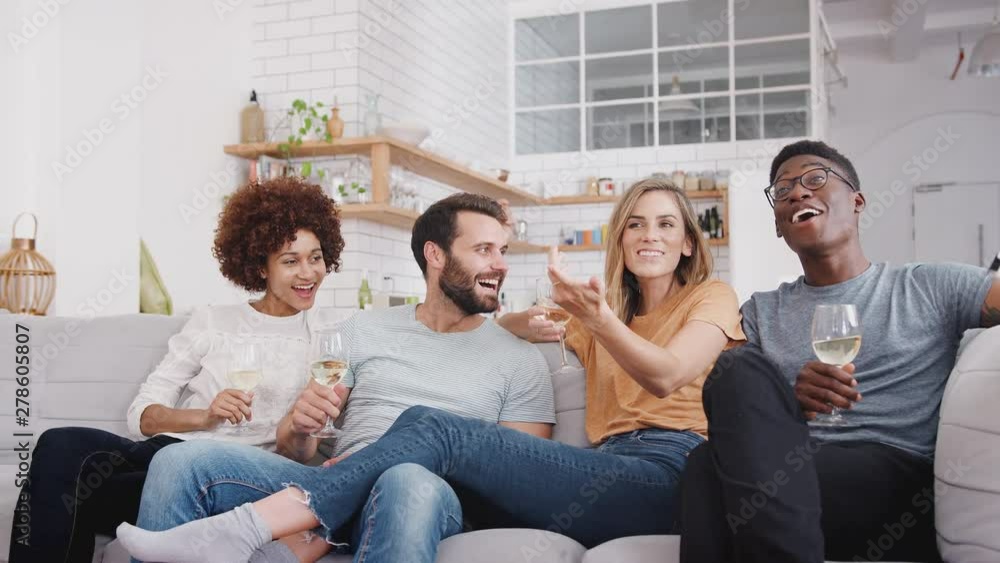 Group Of Friends Sitting On Sofa And Watching Movie At Home Whilst Drinking Wine Group Of Friends Sitting On Sofa And Watching Movie At Home Whilst Drinking Wine