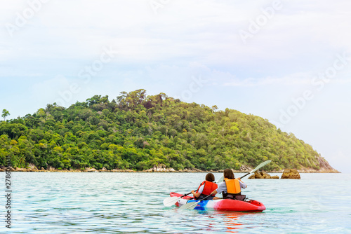 Two woman tourists are mother and daughter travel by boat with a kayak under sunlight of summer at Ko Lipe enjoy the beautiful nature the sea and island in morning, Tarutao National Park, Satun, Thail