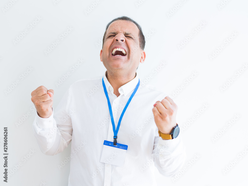 Middle age business man wearing ID card over white background very happy and excited doing winner gesture with arms raised, smiling and screaming for success. Celebration concept. Middle age business man wearing ID card over white background very happy and excited doing winner gesture with arms raised, smiling and screaming for success. Celebration concept.