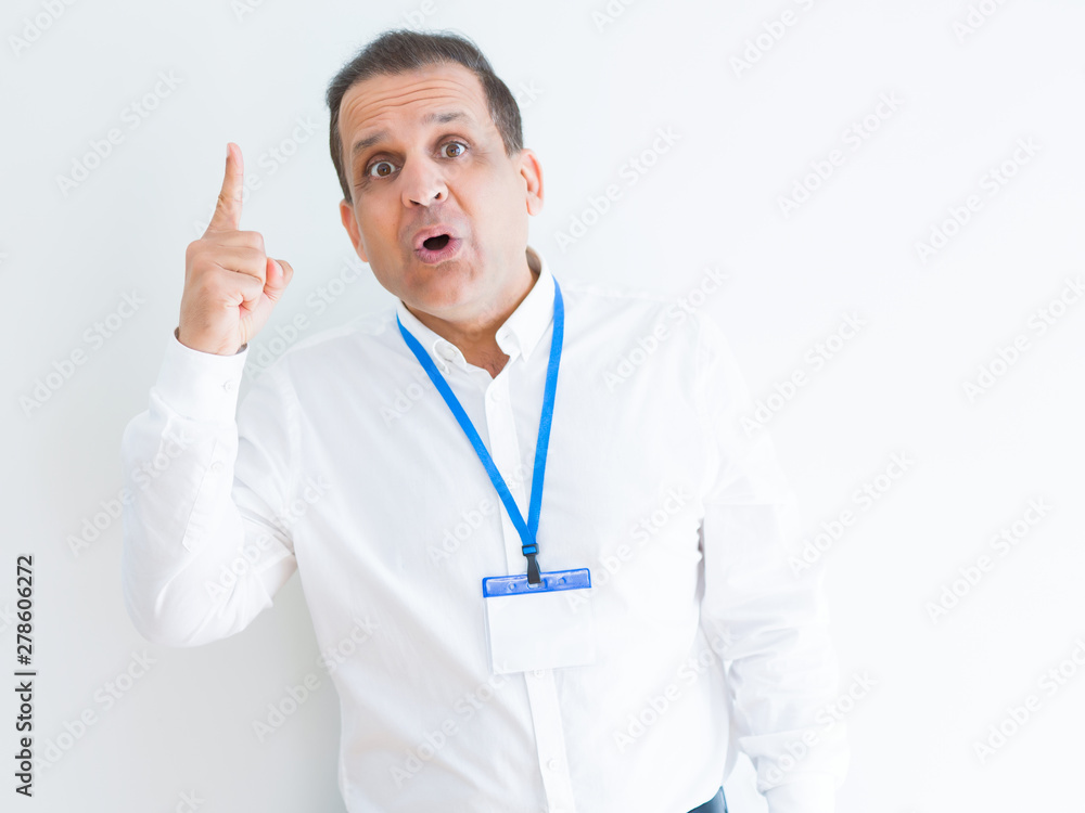 Middle age business man wearing ID card over white background pointing finger up with successful idea. Exited and happy. Number one. Middle age business man wearing ID card over white background pointing finger up with successful idea. Exited and happy. Number one.