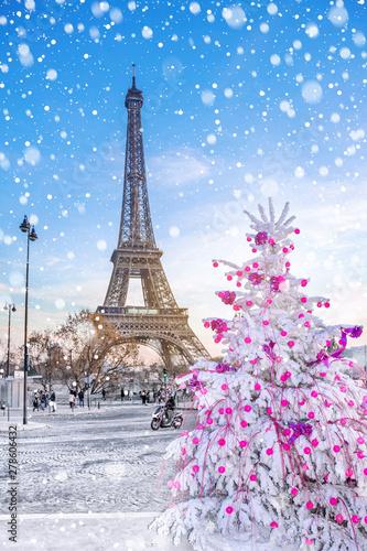Eiffel Tower is the main attraction of Paris on the background of Christmas trees covered by snow in winter. Travel Greeting Card from Paris with love, France