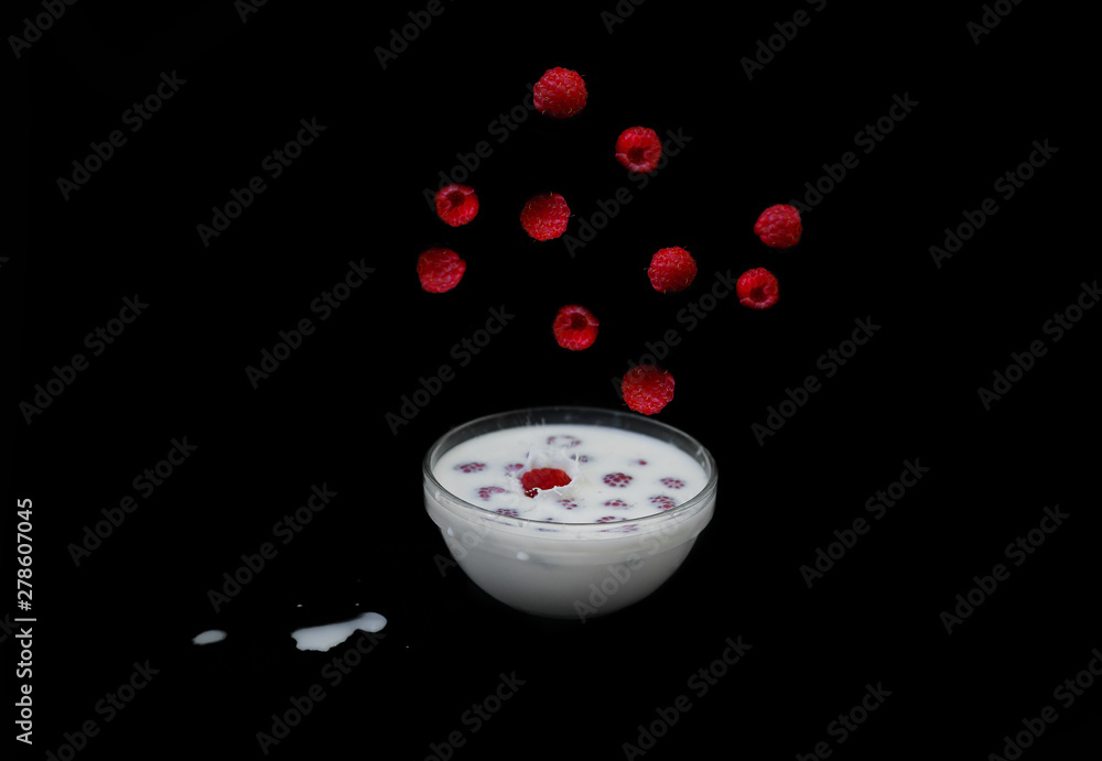 Raspberries falling into milk with a black background. Splashes of milk. Raspberries falling into milk with a black background. Splashes of milk.