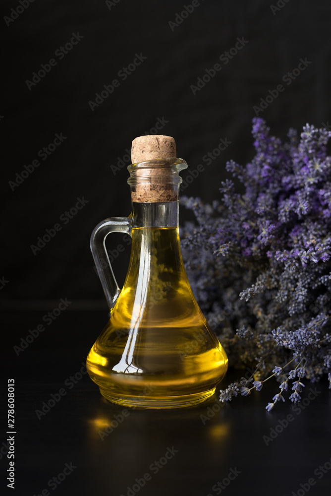 glass bottle with fragrant lavender oil on the background of a purple bouquet.
