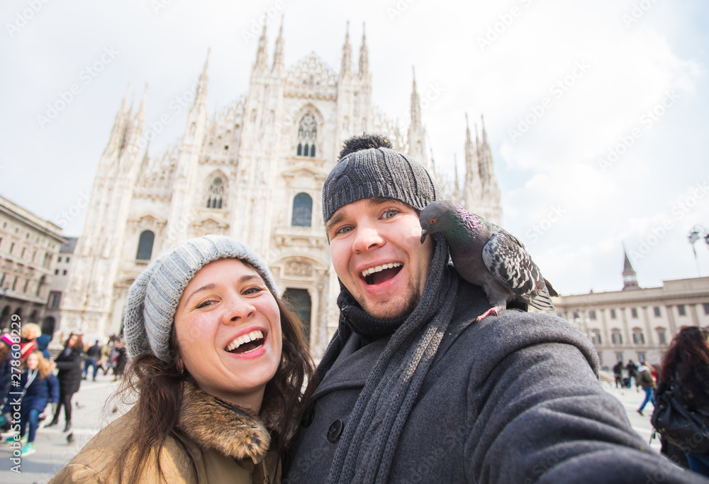 Travel, Italy and funny couple concept - Happy tourists taking a self portrait with pigeons in front of Duomo cathedral, Milan