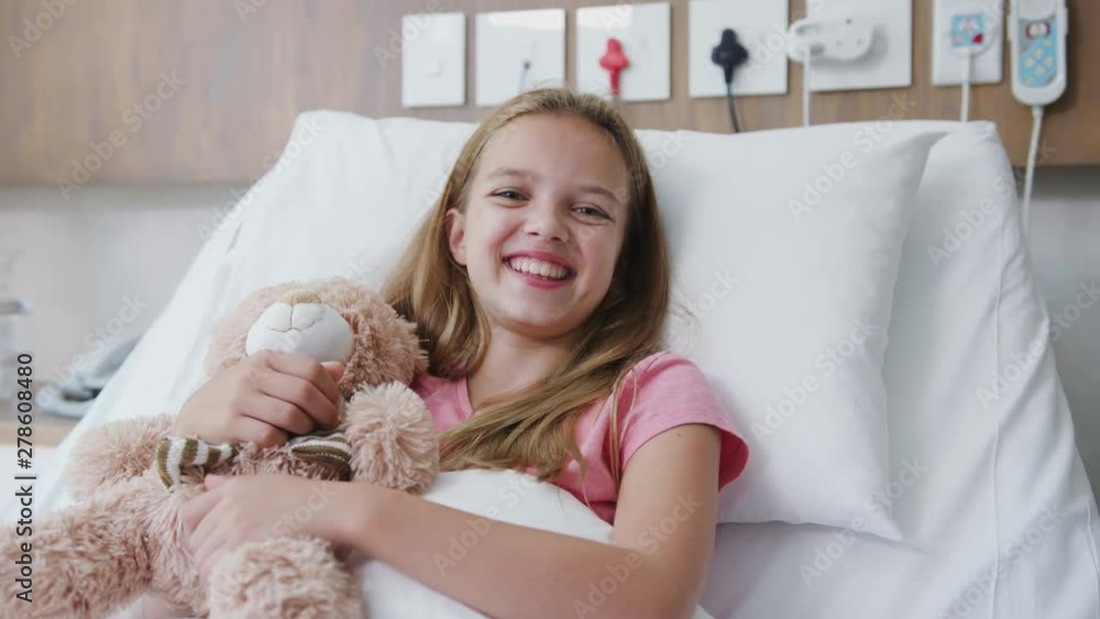 Mother Visiting Daughter Lying In Bed In Hospital Ward And Giving Her Teddy Bear Mother Visiting Daughter Lying In Bed In Hospital Ward And Giving Her Teddy Bear