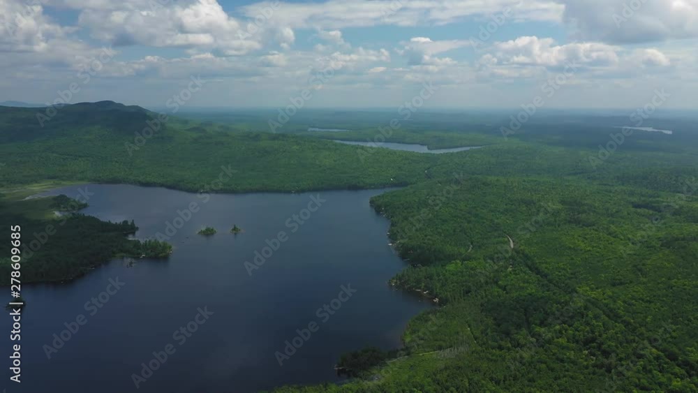 Flying high above a maine lake as a white float plane flies close to the water AERIAL Flying high above a maine lake as a white float plane flies close to the water AERIAL