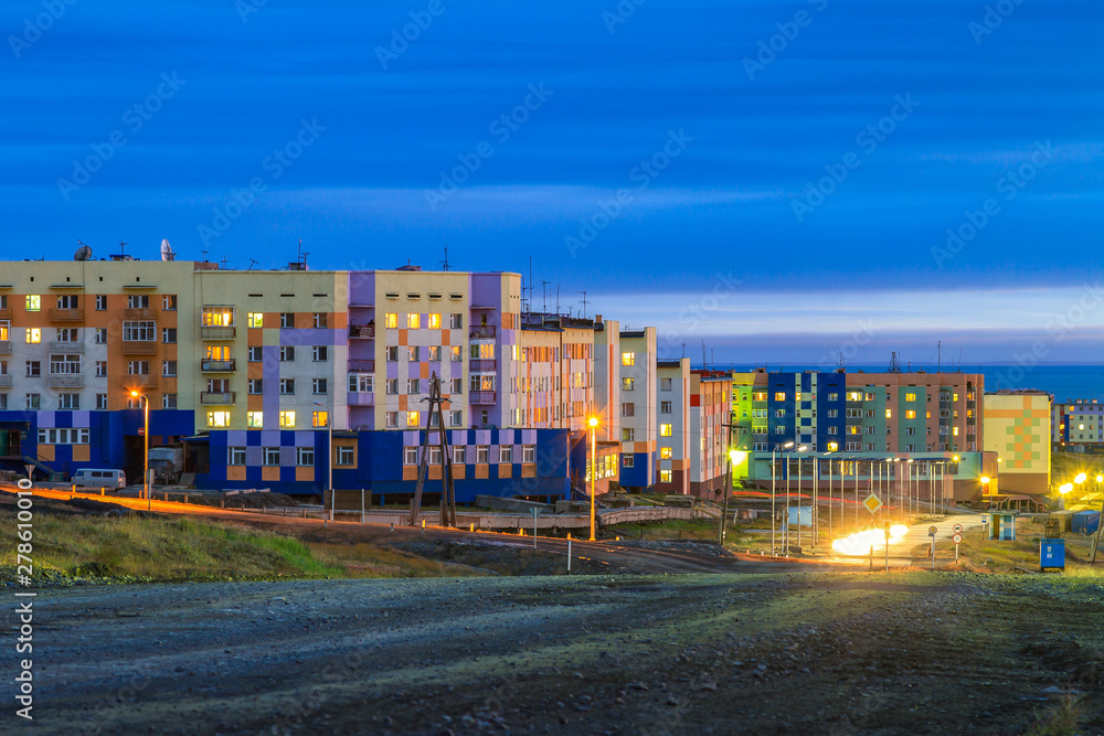 Fototapeta premium Wieczorem gród. Małe północne miasto w Arktyce. Pevek to najbardziej wysunięte na północ miasto Rosji. Wielobarwne budynki i jasne oświetlenie uliczne o zmierzchu. Pevek, Chukotka, Syberia, rosyjski Daleki Wschód.