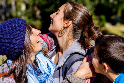 Smiling mother and sons hugging in a forest
