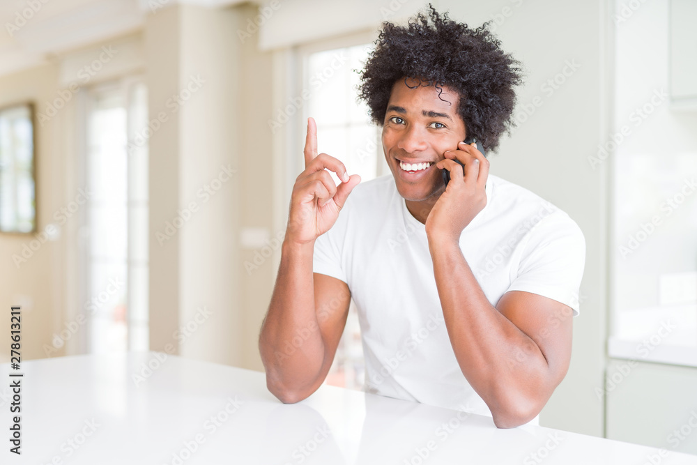 African American business man talking on the phone surprised with an idea or question pointing finger with happy face, number one African American business man talking on the phone surprised with an idea or question pointing finger with happy face, number one