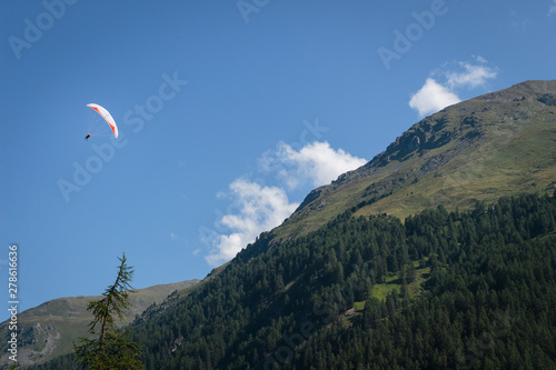 Single colorful paraglider flying in the Pennine Alps near Zinal. Val d'Anniviers, Valais, Switzerland