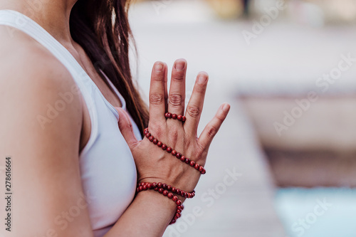 close up view of unrecognizable young asian woman doing yoga in a park. Sitting on the bridge with praying hands position and using Mala necklace. Yoga and healthy lifestyle concept photo