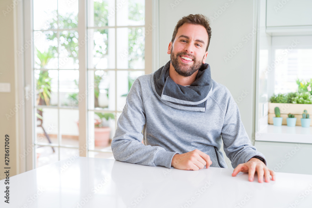 Handsome man wearing casual sweatshirt at home and smiling positive Handsome man wearing casual sweatshirt at home and smiling positive