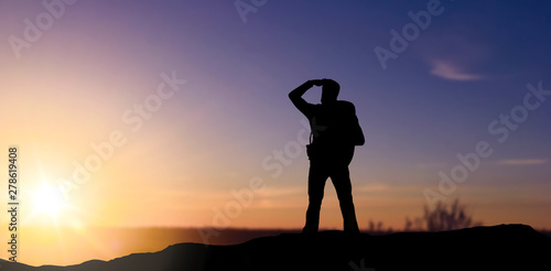 travel  tourism and hike concept - silhouette of male tourist looking far away over sunset background