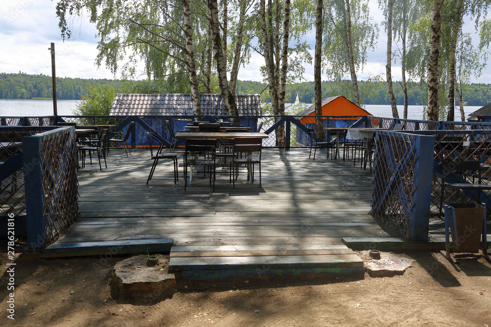 Part of a cozy beach cafe without visitors on the banks of the summer river