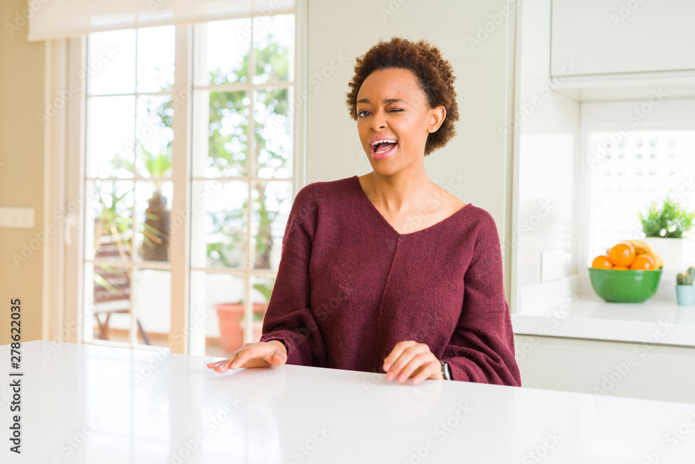Young beautiful african american woman at home winking looking at the camera with sexy expression, cheerful and happy face.