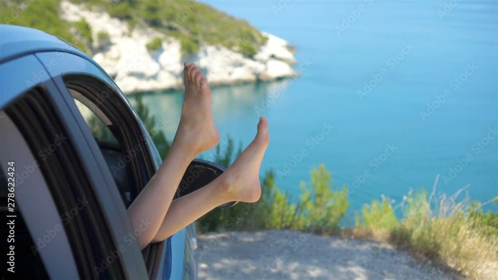 Close up of little girl feet showing from car window background sea Close up of little girl feet showing from car window background sea