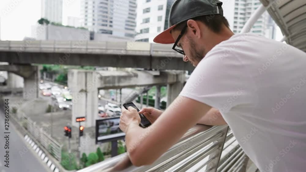 Young caucasian man with glasses and beard using smartphone outdoors. Modern cityscape background. Enjoying vacation travel adventure. Young caucasian man with glasses and beard using smartphone outdoors. Modern cityscape background. Enjoying vacation travel adventure.