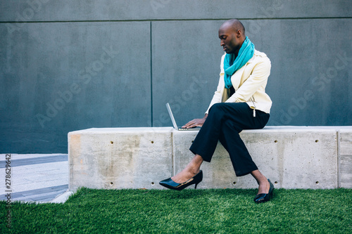 Man wearing high heels and working on laptop