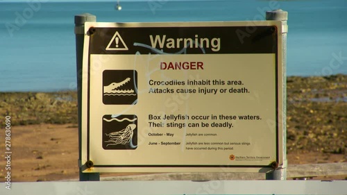 A cautionary sign at the beach warning about the deadly dangers of crocodiles and box jellyfish photo