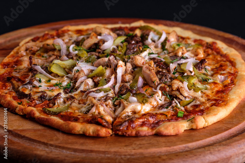 Gluten Free BBQ Chicken Pizza with lots of vegetable fillings, pickles and meat slices on a wooden board.