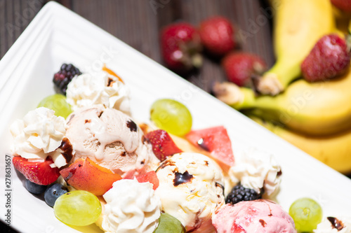 Plate of healthy fresh fruit salad with ice cream on the wooden background.
