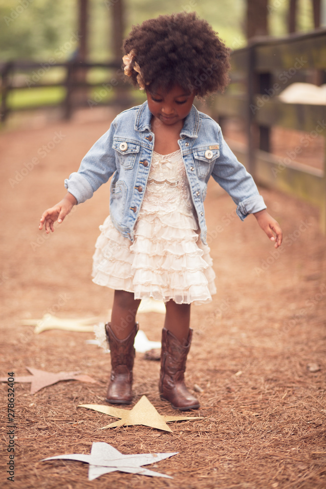 Little girl looking down at paper stars on pathway