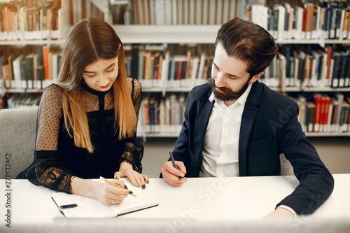 Students in a library. Guy in a black suit. Student with a books.