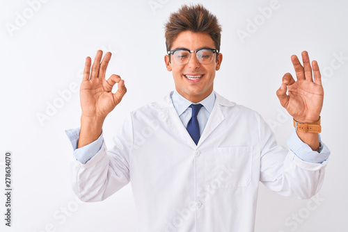 Young handsome sciencist man wearing glasses and coat over isolated white background relaxed and smiling with eyes closed doing meditation gesture with fingers. Yoga concept. photo
