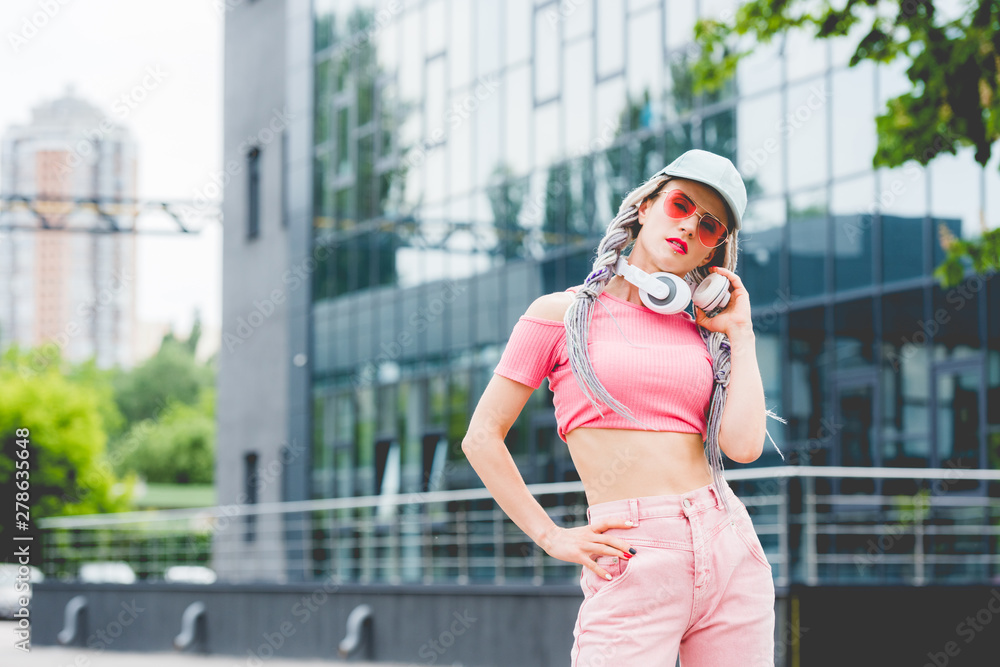 Fototapeta premium stylish girl in sunglasses with headphones posing and looking at camera