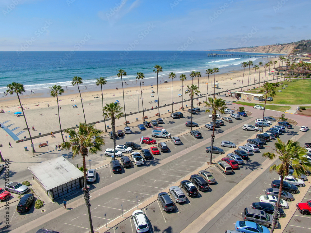 Aerial view of parking lot with cars in front of the beach & ocean during blue summer day. La Jolla, San Diego, California, USA. 
