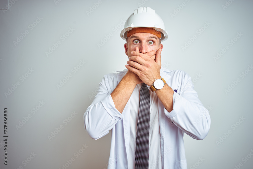 Young handsome engineer man wearing safety helmet over isolated background shocked covering mouth with hands for mistake. Secret concept. Young handsome engineer man wearing safety helmet over isolated background shocked covering mouth with hands for mistake. Secret concept.