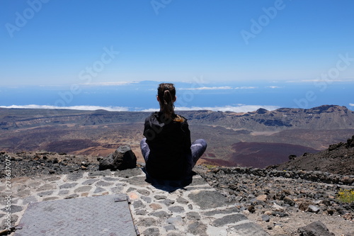 Woman looking at a dry and rocky volcanic landscape on Teide - Spain