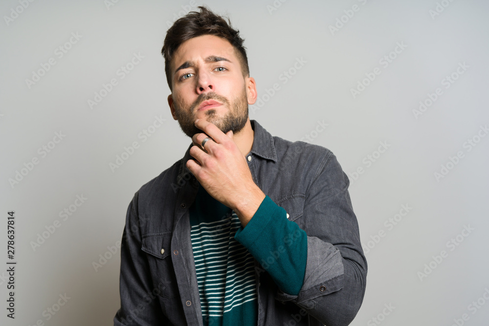 Young handsome man possing and modeling over grey isolated background Young handsome man possing and modeling over grey isolated background
