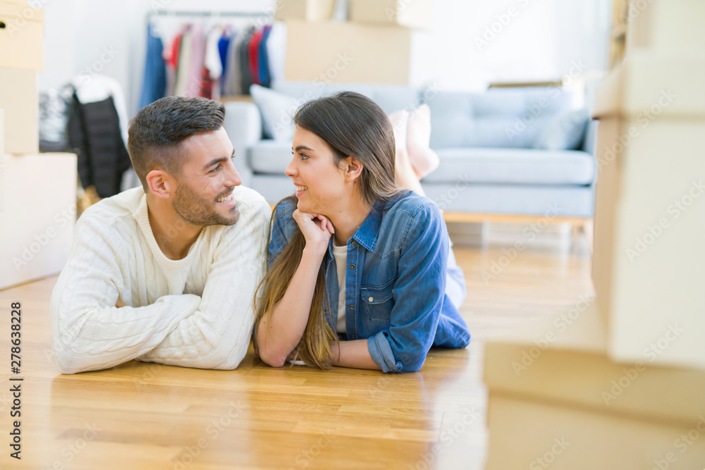 Young beautiful couple lying on the floor of new house, smiling in love very happy for moving to new apartment Young beautiful couple lying on the floor of new house, smiling in love very happy for moving to new apartment