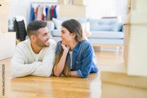 Young beautiful couple lying on the floor of new house, smiling in love very happy for moving to new apartment