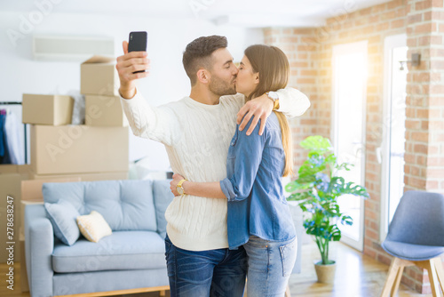 Beautiful couple taking a selfie photo using smartphone at new apartment, smiling happy for new house © Krakenimages.com