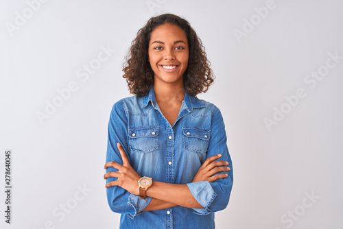 Young brazilian woman wearing denim shirt standing over isolated white background happy face smiling with crossed arms looking at the camera. Positive person. photo