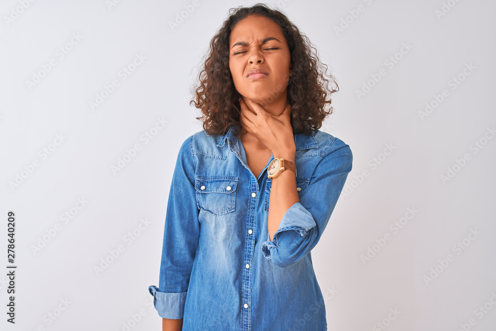 Young brazilian woman wearing denim shirt standing over isolated white background Touching painful neck, sore throat for flu, clod and infection Young brazilian woman wearing denim shirt standing over isolated white background Touching painful neck, sore throat for flu, clod and infection