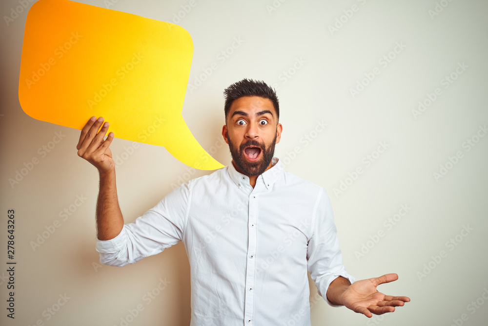 Young arab indian hispanic man holding speech bubble over isolated white background very happy and excited, winner expression celebrating victory screaming with big smile and raised hands Young arab indian hispanic man holding speech bubble over isolated white background very happy and excited, winner expression celebrating victory screaming with big smile and raised hands