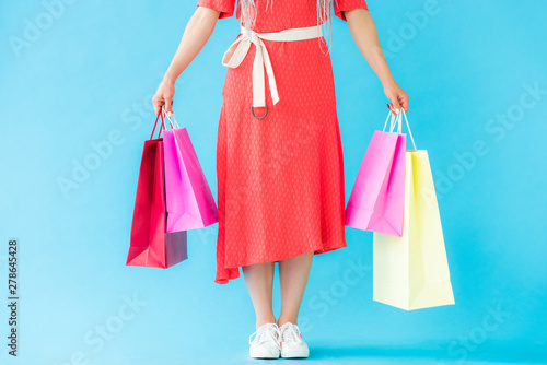 cropped view of fashionable girl with shopping bags on turquoise