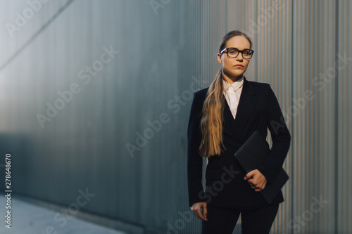 Young business lady in glasses standing in front of the building.