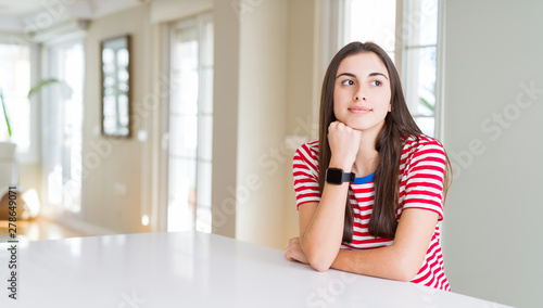 Beautiful young woman wearing casual stripes t-shirt with hand on chin thinking about question  pensive expression. Smiling with thoughtful face. Doubt concept.