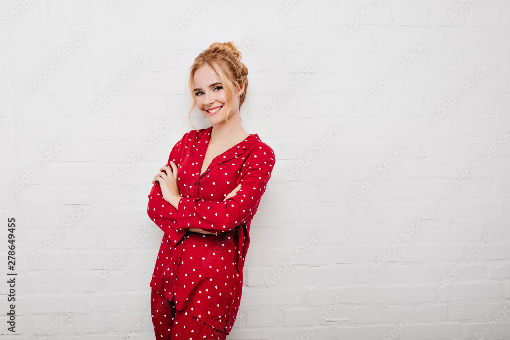 Positive curly girl in pajama standing in confident pose. Studio portrait of relaxed female model wears red night-suit and posing with arms crossed. Positive curly girl in pajama standing in confident pose. Studio portrait of relaxed female model wears red night-suit and posing with arms crossed.