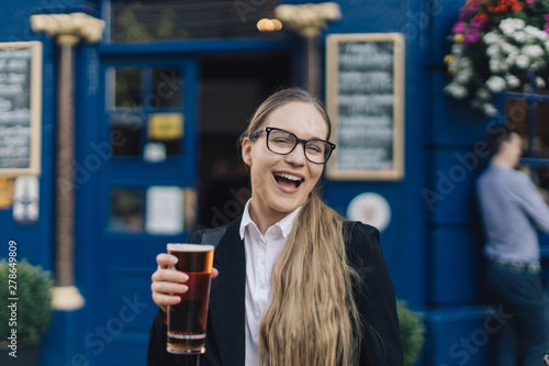 Tableau sur toile Young business lady in glasses standing by the pub with a pint of the beer