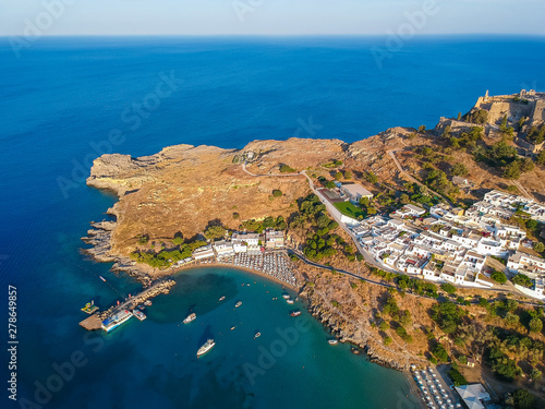 Aerial birds eye view drone photo of village Lindos, Rhodes island, Dodecanese, Greece. Sunset panorama with castle, Mediterranean sea coast. Famous tourist destination in South Europe.